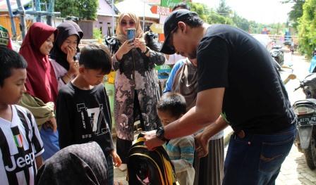 Kepala Dinas Pendidikan Kota Banjarbaru menyerahkan tas kepada anak-anak yang terdampak banjir. (Sumber Foto:Disdik Banjarbaru)